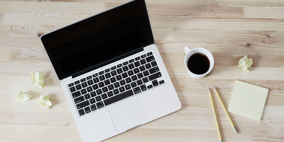 opened laptop with a cup of black coffee and two yellow pens accompanied by some sticky notes suggests brainstorm process behind creating agency pitch deck